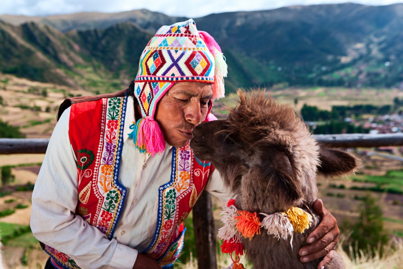 Peruvian man kissing llama near Pisac, Sacred Valley, Peru